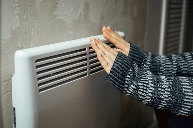 Woman warming her hands by a radiator